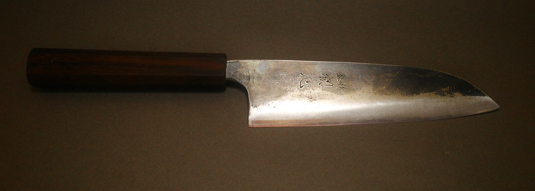 The same carbon steel knife after sharpening, edge restored with the patina left intact