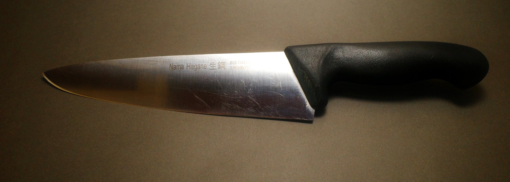Well-used chef knife before sharpening, blade scratched and dull